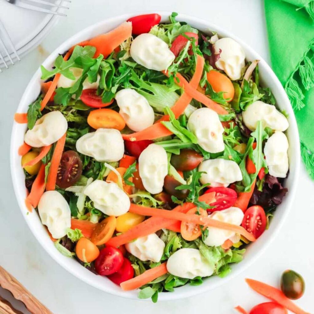 Featured image for Halloween mixed green salad in a white bowl.