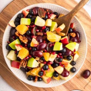 Square image of a fall fruit salad in a white bowl.
