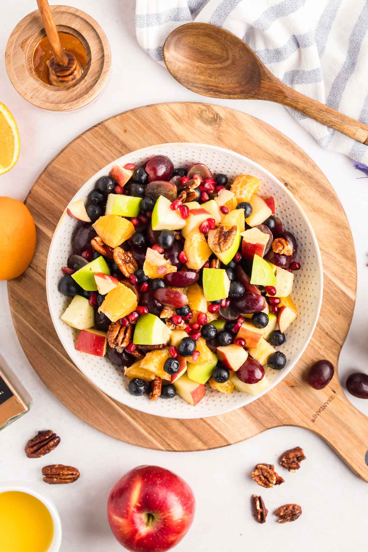 Fresh fall fruit salad in a bowl sitting on a cutting board.