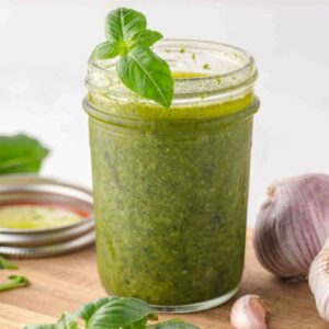 Basil balsamic dressing in a jar garnished with a basil leaf.