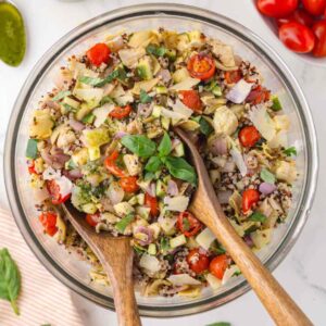 Featured image for roasted vegetable salad being tossed with basil balsamic dressing.