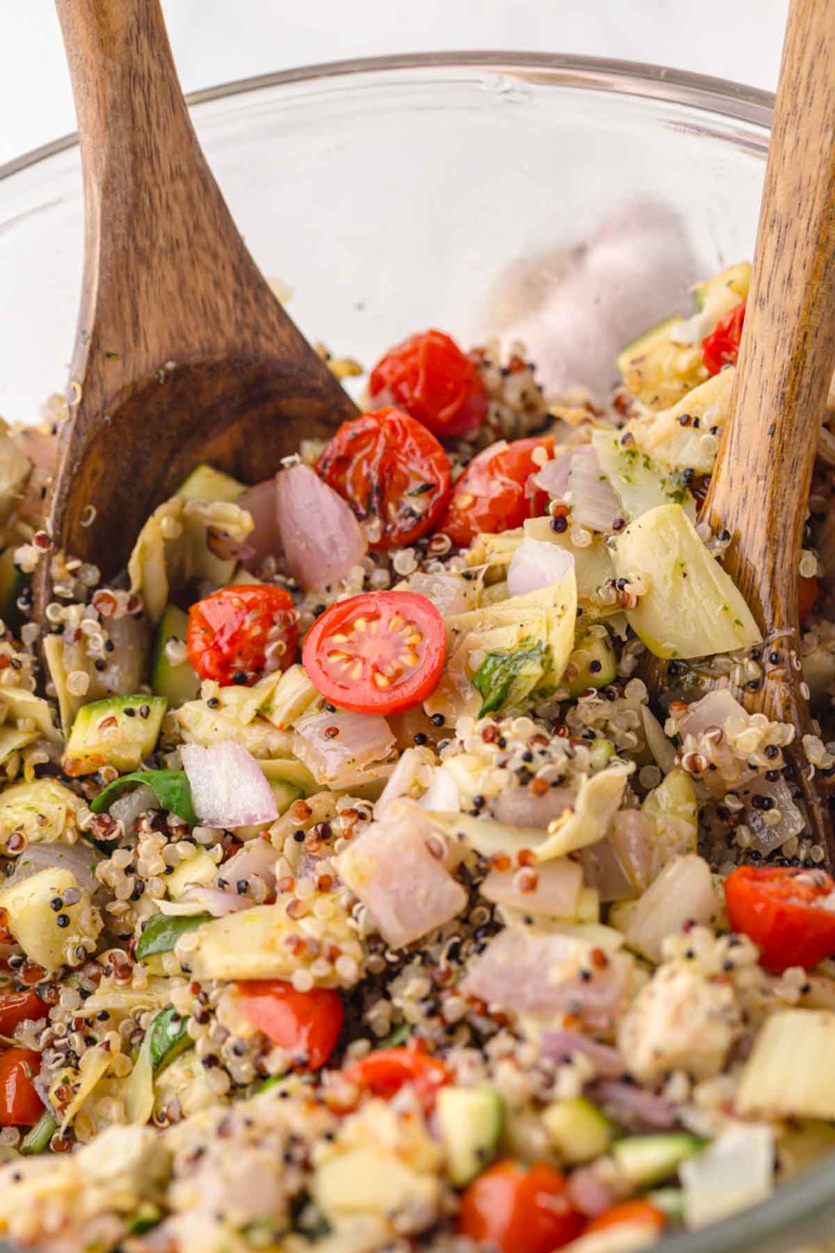 Roasted veggie salad being tossed with the basil dressing.