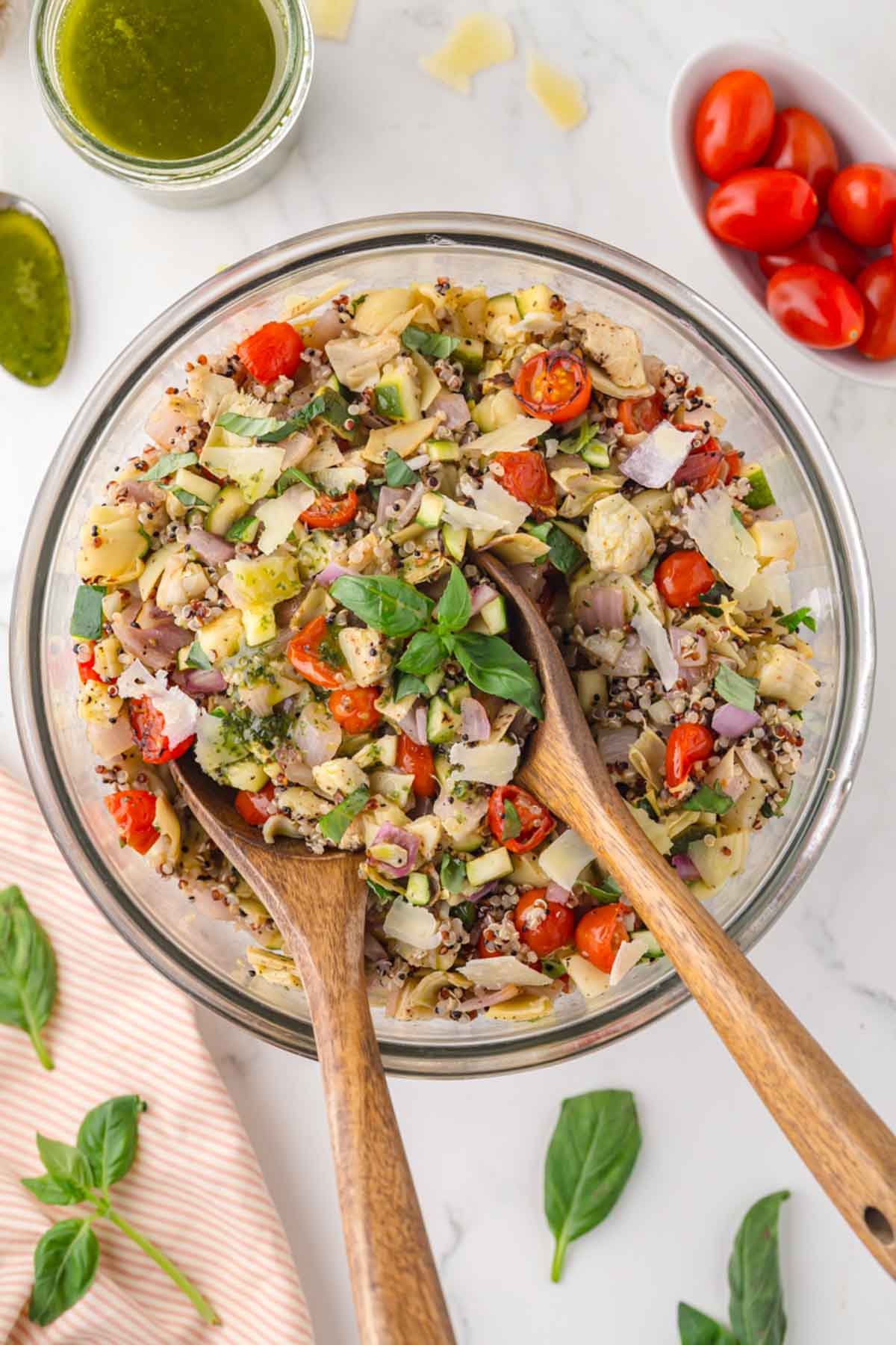 Roasted vegetable salad with basil balsamic dressing in a glass bowl being tossed.