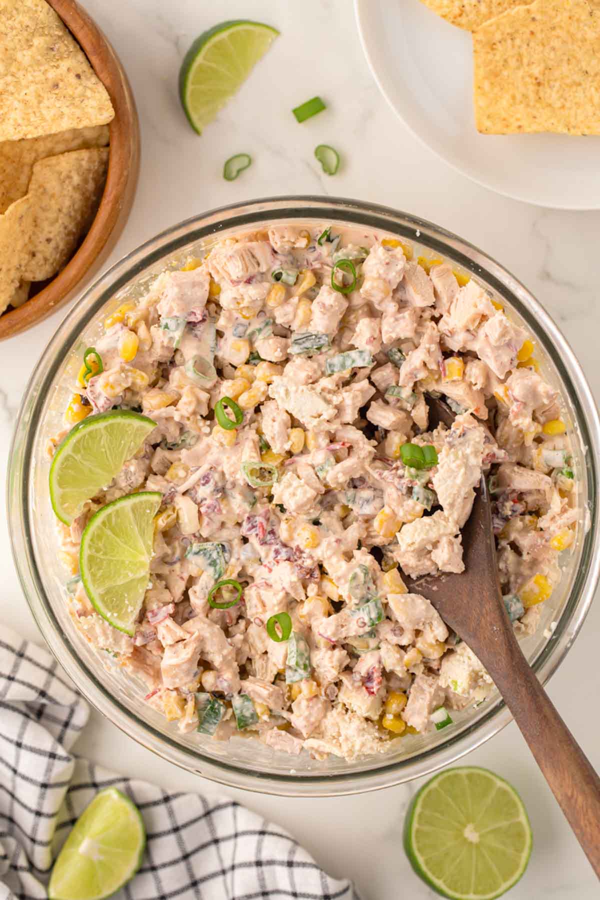 Street corn chicken salad in a glass bowl with limes.