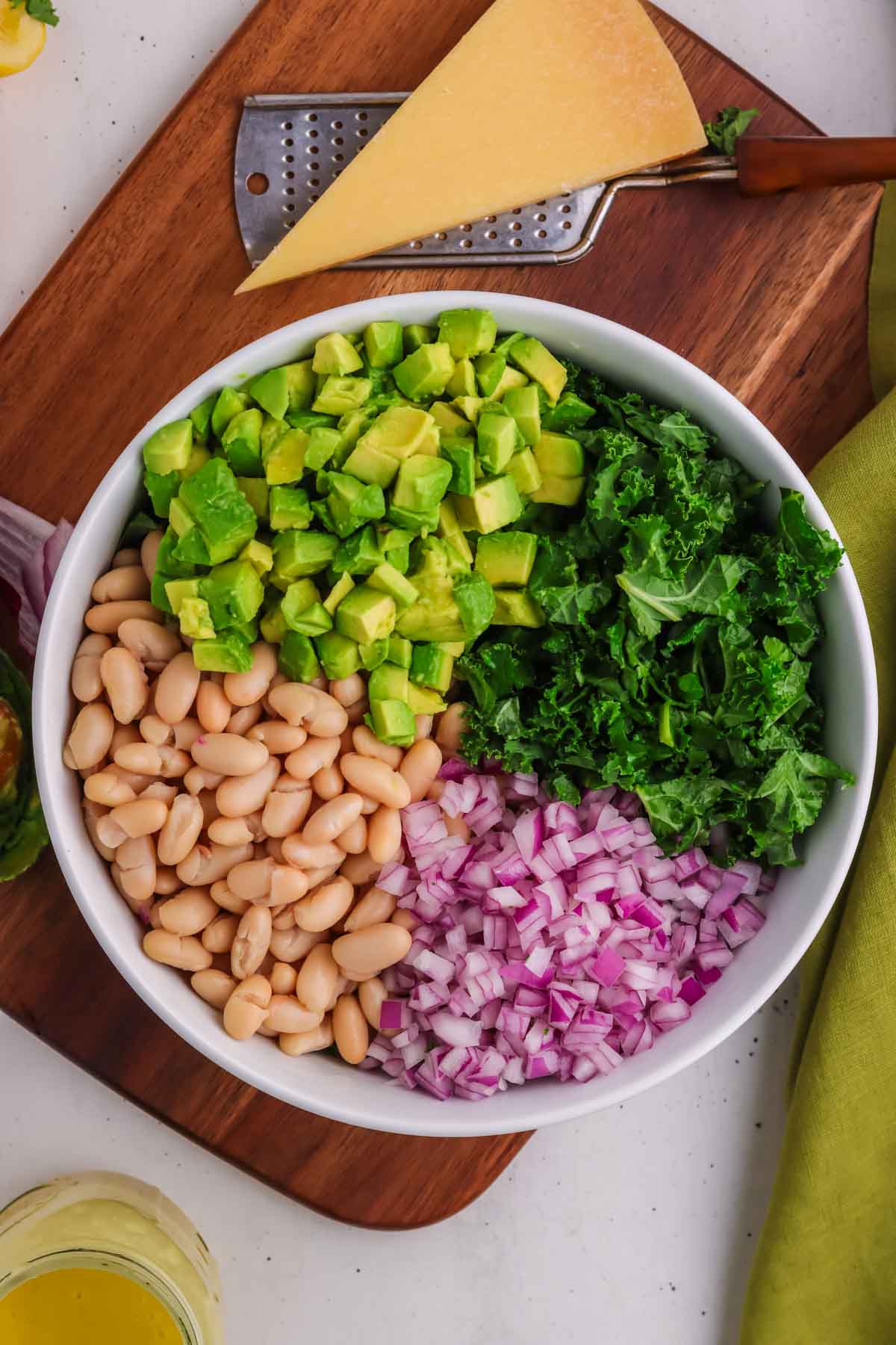 All ingredients for the kale and white bean salad in a bowl before being tossed with the dressing.
