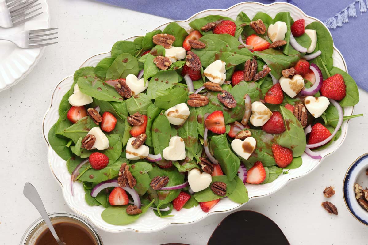 Strawberry and spinach salad with mozzarella. hearts on a white serving platter.