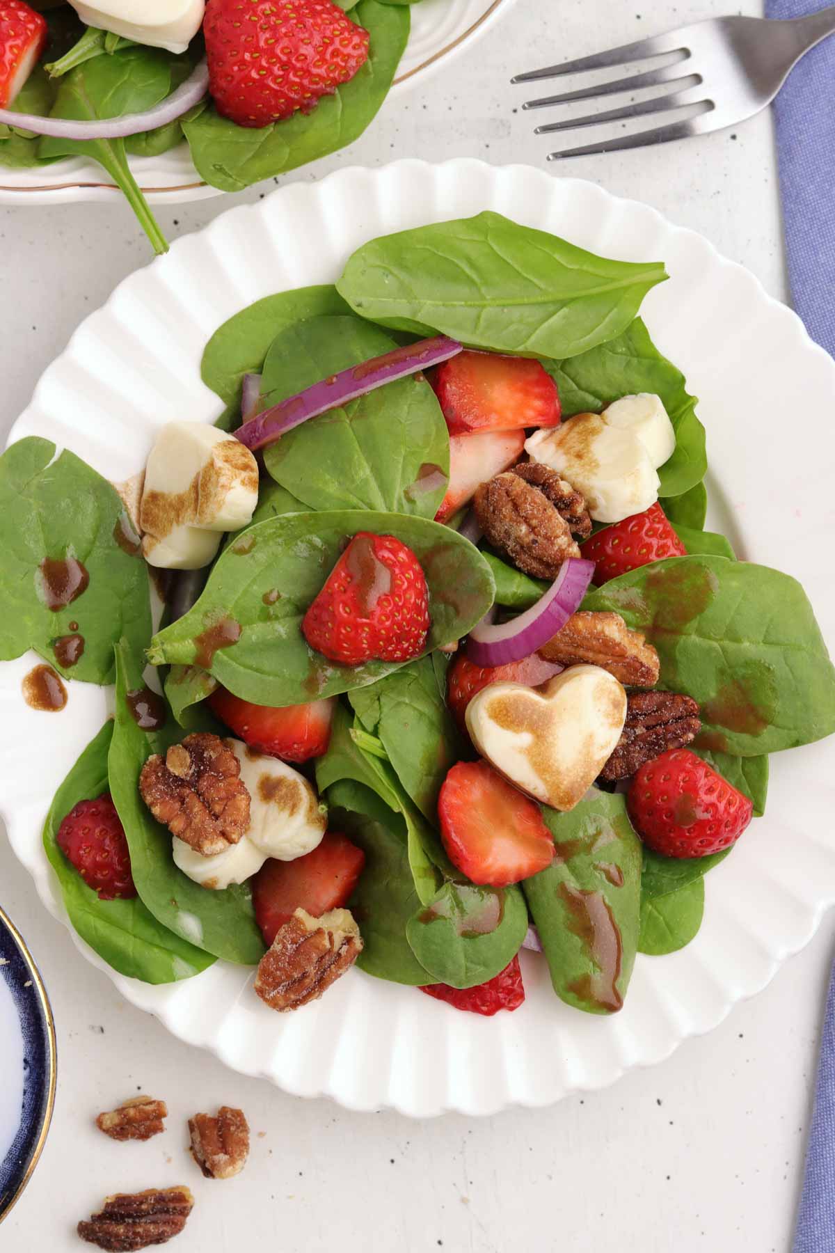 Strawberry and spinach salad with mozzarella. hearts on a white plate.